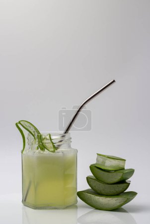 Aloe Vera Saft in einem Glas mit geschnittener und gestapelter Aloe Vera isoliert auf weißem Hintergrund.