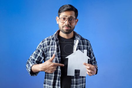 Photo for Indian man showing house loan concept, isolated on blue background. - Royalty Free Image