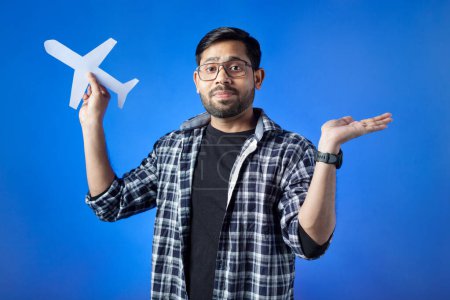 Photo for Travel destination, journey, airplane, ticket. A man clutching paper cut airplane and showing open palm hand gesture. - Royalty Free Image