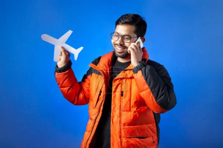 Photo for Travel destination, journey, passenger. A man talk on phone and holding paper cutting aeroplane. - Royalty Free Image
