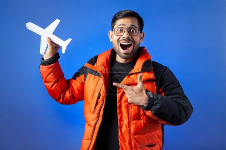 Photo for Indian ethnicities, passenger, journey. One man surprised and pointing finger towards the paper cut airplane. - Royalty Free Image