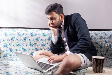 Photo for Depressed sad man looking at laptop screen wearing half suit - Royalty Free Image