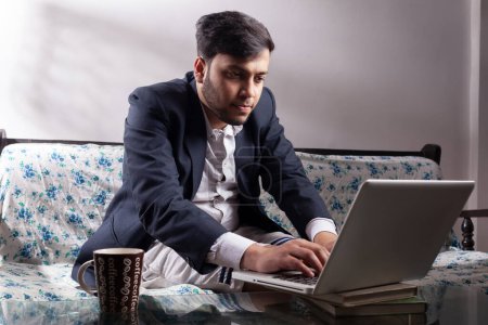 Photo for Busy businessman working on laptop at home sitting on sofa - Royalty Free Image