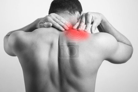 Photo for Trapezius muscle pain, Black and white shot portrait of a man touching neck injury area with pain highlighted in red glow. - Royalty Free Image