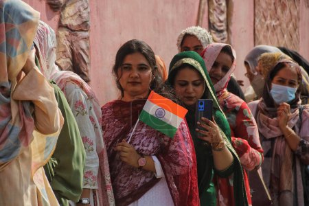 Téléchargez les photos : 15 août 2023, Srinagar Cachemire, Inde : Une jeune fille tient le drapeau national de l'Inde alors qu'elle fait la queue devant le stade Bakshi pour assister aux célébrations de la 77e fête de l'indépendance de l'Inde à Srinagar - en image libre de droit
