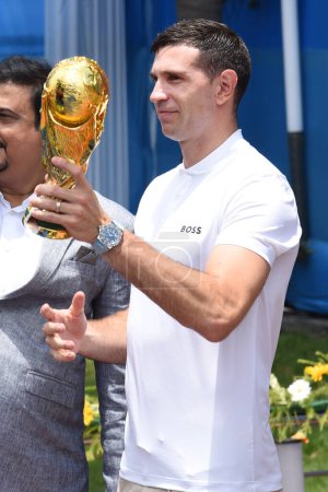 Photo for July 05,2023, Kolkata, India: 2022 FIFA World Cup winning, Argentina's  goalkeeper Emiliano Martinez, poses holding a replica of FIFA World Cup   in front of the statue of late Argentine soccer legend Diego Armando Maradona - Royalty Free Image