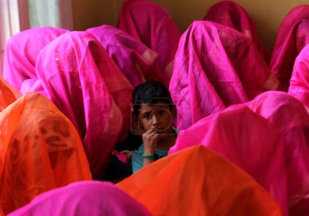 Photo for June 15,2023, Srinagar Kashmir, India : A child looks on as Muslim brides gather in a room during a mass marriage event in Srinagar.  At least 61 sets of couples participated in the mass marriage event organized by 'We the helping hands foundation' - Royalty Free Image