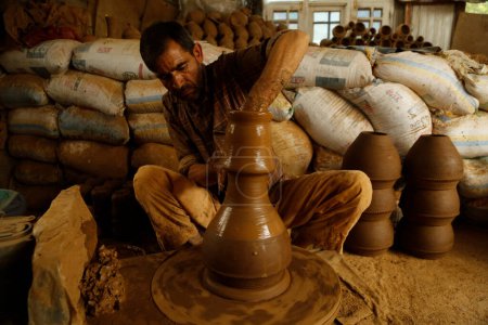 Photo for August 10,2023, Srinagar Kashmir, India : Mohammad Yousuf Kumar, a Kashmiri potter works clay to make an Tumbaknari (a Kashmiri musical drum) at his workshop on the outskirts of Srinagar. In Kashmiri weddings - Royalty Free Image