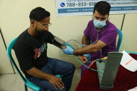 Téléchargez les photos : 22 août 2023, Srinagar Cachemire, Inde : Un médecin vérifie la pression artérielle d'un journaliste lors d'un camp médical gratuit pour la fraternité des journalistes à Srinagar - en image libre de droit