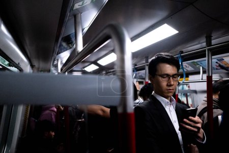 Photo for A man checks his cell phone while traveling on the subway - Royalty Free Image