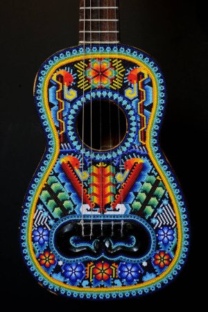 Foto de Una guitarra decorada con diseños y ornamentos hechos de cuentas multicolores hechas por artesanos indígenas de las comunidades Huichol de los estados Jalisco y Nayarit de la cultura Wixarika - Imagen libre de derechos
