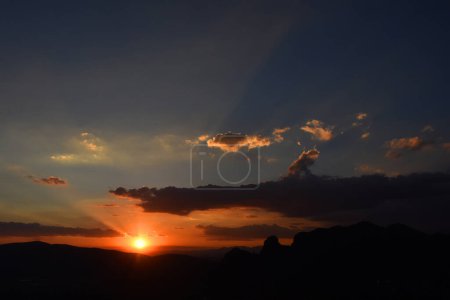 Foto de El sol se pone detrás de las montañas durante una puesta de sol de invierno para apreciar el paisaje en la zona montañosa de Tepoztlan. - Imagen libre de derechos