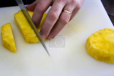 Téléchargez les photos : Gros plan de la personne coupe des tranches d'ananas frais - en image libre de droit