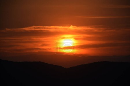 Foto de El sol se pone detrás de las montañas durante una puesta de sol de invierno para apreciar el paisaje en la zona montañosa de Tepoztlan. - Imagen libre de derechos