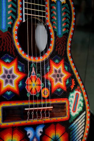 Photo for A guitar decorated with designs and ornaments made of multicolored beads made by indigenous artisans from the Huichol communities of the Jalisco and Nayarit states of the Wixarika Culture - Royalty Free Image