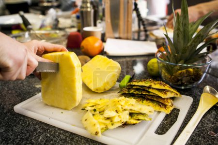 Téléchargez les photos : Une personne coupe des tranches d'ananas frais - en image libre de droit