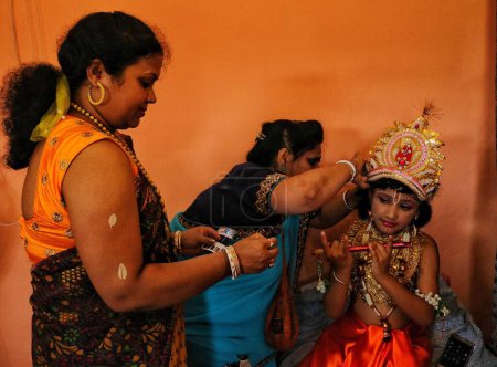 Foto de Septiembre 07,2023, Srinagar Cachemira, India: Una mujer hindú viste a un niño como la deidad hindú Krishna antes de una procesión para marcar a 'Krishna Janmashtami' en Srinagar. Janmashtami es un festival hindú el aniversario del nacimiento del Señor hindú Krishna - Imagen libre de derechos