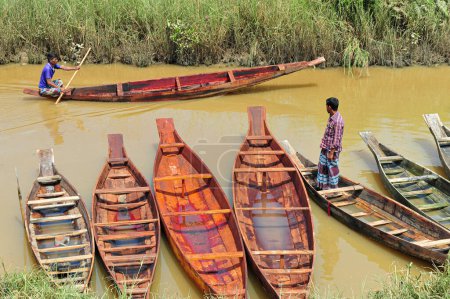Photo for Sylhet, Bangladesh - 09 September 2023: Rural buyer getting back with his newly bought wooden boat at Salutikar Bazar of Sylhet, Bangladesh - Royalty Free Image