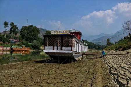 Téléchargez les photos : Srinagar, Cachemire, Inde - 12 septembre 2023 : Pour maintenir l'équilibre de la péniche sur les lits secs de la rivière Jhelum, les propriétaires ont fixé des bûches de bois au fond, alors que les niveaux d'eau continuent de reculer dans la rivière en raison de la période sèche en cours à Srinagar - en image libre de droit