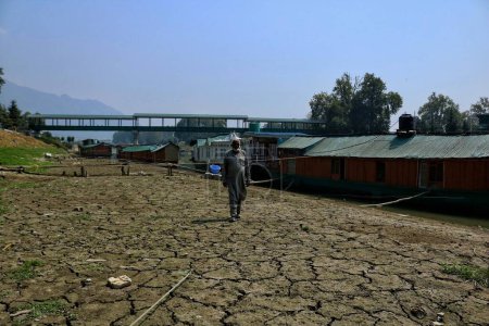 Foto de Srinagar Cachemira, India - 12 de septiembre de 2023: Un hombre camina por los parches secos a orillas del río Jhelum en Srinagar. El nivel del agua en el río Jhelum ha registrado una caída significativa debido a las lluvias deficitarias en Cachemira - Imagen libre de derechos