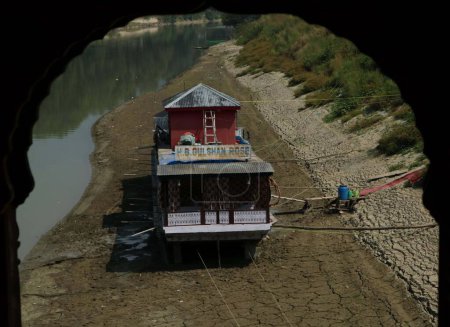 Photo for Srinagar, Kashmir, India - September 12,2023: To keep  balance of  houseboat on the dry beds of River Jhelum, owners have fixed wooden logs at the bottom, as the water levels continue to recede in the river due to the ongoing dry spell in Srinagar - Royalty Free Image