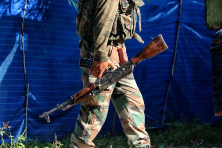 Foto de 15 de septiembre de 2023, Srinagar Cachemira, India: Un soldado del ejército indio lleva su rifle de asalto cerca del lugar del tiroteo entre militantes y fuerzas de seguridad que entró al tercer día en la aldea Gadole de Kokernag en el distrito de Anantnag - Imagen libre de derechos