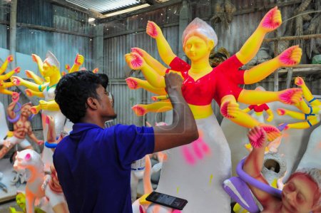 Téléchargez les photos : 23 septembre 2023 Sylhet-Bangladesh : Un artiste idolâtre travaille sur la peinture de structures d'une divinité hindoue en préparation du prochain Festival Durga Puja 2023 - en image libre de droit