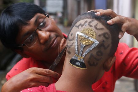 Foto de Octubre 02, 2023, Kolkata City, India,: Peluquería india, Robin Das terminar el corte de pelo colorear un diseño de la Copa Mundial de Cricket hacer en la cabeza de un joven en una peluquería - Imagen libre de derechos