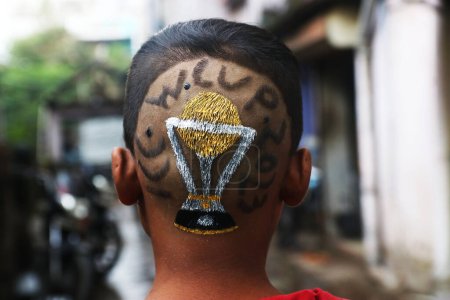 Foto de Octubre 02, 2023, Kolkata City, India,: Peluquería india, Robin Das terminar el corte de pelo colorear un diseño de la Copa Mundial de Cricket hacer en la cabeza de un joven en una peluquería - Imagen libre de derechos