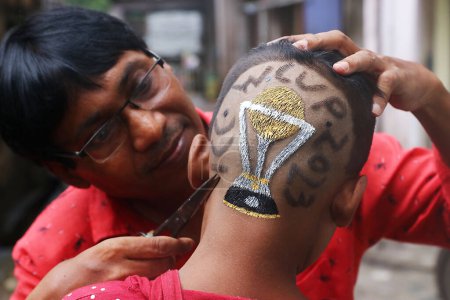 Photo for October 02, 2023, Kolkata City, India,: Indian hair dresser, Robin Das finish the haircut coloring a Cricket World Cup design make on the head of a young  at a hair salon - Royalty Free Image