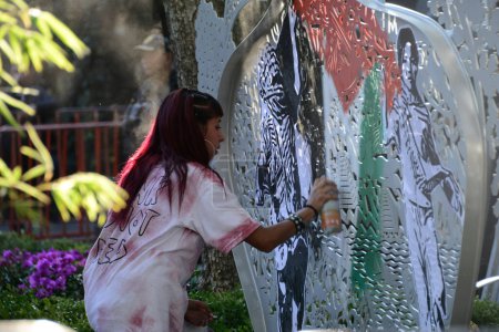 Photo for October 12, 2023, Mexico City, Mexico: A woman graffitis the  Palestine flag  during  a rally outside the Israeli Embassy in Mexico to protest of the recent attacks by the Israeli army against the people of Palestine - Royalty Free Image