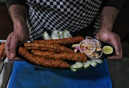 Photo for October 20,2023, Srinagar Kashmir, India : A chef shows a Kashmiri traditional food know as  Kabab after cooking it as part of the  International Chefs Day in Srinagar at Tao Cafe Restaurant - Royalty Free Image