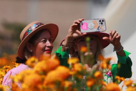 Foto de 20 de octubre de 2023, Atlixco, México: Dos mujeres toman una foto en el campo de flores de Cempasuchil durante la cosecha en el estado de Puebla, los agricultores las distribuyen en los mercados locales para que puedan ser vendidas a la gente para decorar las ofrendas - Imagen libre de derechos