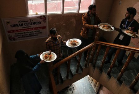 Téléchargez les photos : 01 novembre 2023, Srinagar Cachemire, Inde : Les gens prennent des tramis (assiettes) pour les servir aux invités lors d'une cérémonie de mariage de masse, à Srinagar - en image libre de droit