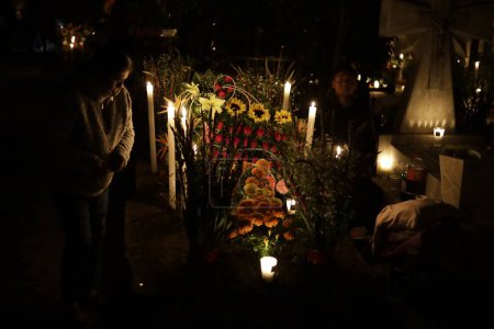Foto de 2 de noviembre de 2023, Ciudad de México, México: Familias decoran las tumbas de sus seres queridos, niños y también vigilan las tumbas de adultos como parte del Festival del Día de los Muertos en el Panteón de San Gregorio Atlapulco en la Alcaldía de Xochimilco - Imagen libre de derechos