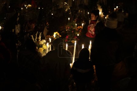 Foto de 2 de noviembre de 2023, Ciudad de México, México: Familias decoran las tumbas de sus seres queridos, niños y también vigilan las tumbas de adultos como parte del Festival del Día de los Muertos en el Panteón de San Gregorio Atlapulco en la Alcaldía de Xochimilco - Imagen libre de derechos