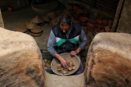Photo for November 02,2023, Srinagar Kashmir, India : Mohammad Umar Kumar, a Kashmiri Muslim potter arranges earthen lamps at his home workshop ahead of the Diwali festival, on the outskirts of Srinagar - Royalty Free Image