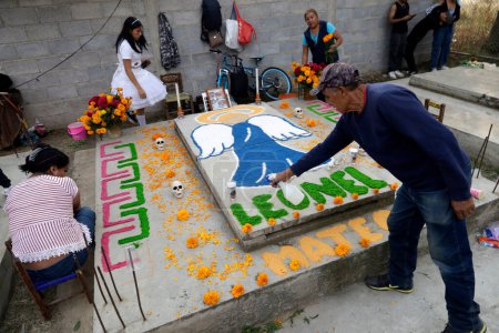 Téléchargez les photos : 2 novembre 2023, Mexico, Mexique : Des parents décorent les tombes de leurs proches avec des sculptures de boue lors de la fête de la Journée des Morts au Panthéon de San Antonio Tecomitl dans le bureau du maire de Milpa Alta à Mexico - en image libre de droit