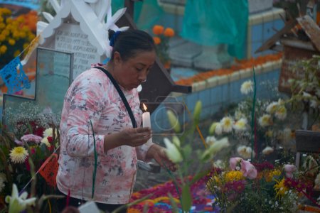 Téléchargez les photos : 2 novembre 2023, Mexico, Mexique : Des parents décorent les tombes avec des fleurs de cempasuchil et illuminent les tombes de leurs proches avec des bougies, remplissant le panthéon de couleur et de folklore - en image libre de droit