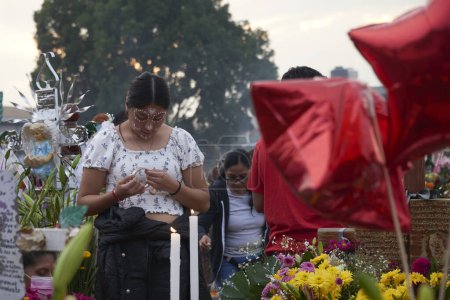 Téléchargez les photos : 2 novembre 2023, Mexico, Mexique : Des parents décorent les tombes avec des fleurs de cempasuchil et illuminent les tombes de leurs proches avec des bougies, remplissant le panthéon de couleur et de folklore, lors des célébrations de la Journée des Morts - en image libre de droit