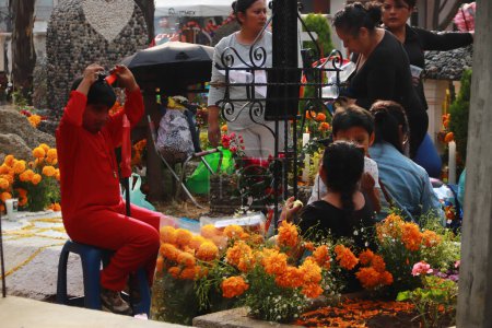 Téléchargez les photos : 2 novembre 2023 à Mexico, Mexique : Des parents assistent au panthéon de San Antonio Tecmitl et sculptent la terre avec des éléments tels que de la sciure, de la chaux et des fleurs, en offrande pour recevoir leurs morts - en image libre de droit