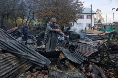 Téléchargez les photos : 11 novembre 2023, Srinagar Cachemire, Inde : Des gens cherchent leurs biens dans les débris après un incendie au lac Dal à Srinagar - en image libre de droit