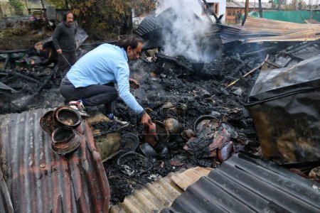Téléchargez les photos : 11 novembre 2023, Srinagar Cachemire, Inde : Des gens cherchent leurs biens dans les débris après un incendie au lac Dal à Srinagar - en image libre de droit