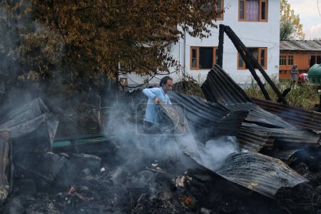 Téléchargez les photos : 11 novembre 2023, Srinagar Cachemire, Inde : Un homme cherche des biens dans les débris après un incendie au lac Dal à Srinagar - en image libre de droit