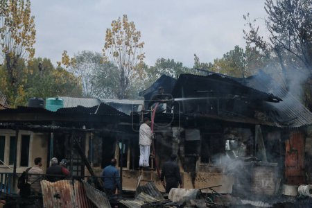Téléchargez les photos : 11 novembre 2023, Srinagar Cachemire, Inde : Des Cachemiris travaillent à éteindre un incendie qui a détruit plusieurs péniches au lac Dal à Srinagar. Un incendie massif a éclaté dans les péniches dans le centre touristique du lac Dal à Srinagar - en image libre de droit