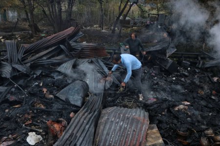 Foto de 11 de noviembre de 2023, Srinagar Cachemira, India: La gente busca sus pertenencias de los escombros después de un incidente de incendio en el lago Dal en Srinagar. Un incendio masivo estalló en las casas flotantes en el centro turístico del lago Dal en Srinagar temprano - Imagen libre de derechos
