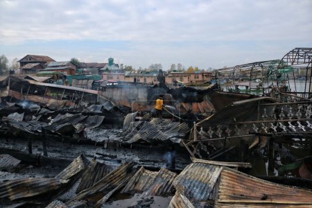 Photo for November 11,2023, Srinagar Kashmir, India : A Kashmiri man works to douse a fire that gutted several houseboats at Dal lake in Srinagar - Royalty Free Image