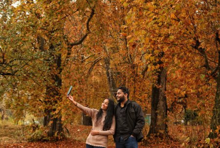Foto de 10 de noviembre de 2023, Srinagar Cachemira, India: Los visitantes toman fotos de selfies en el Jardín Mughal cubierto con hojas caídas de poderosos árboles de Chinar en Nishat en Srinagar. Los colores otoñales están alcanzando su pico con los árboles, particularmente el Chinar - Imagen libre de derechos