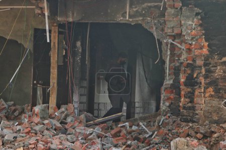 Téléchargez les photos : 17 novembre 2023, Srinagar Cachemire, Inde : Un homme inspecte une maison endommagée une fusillade dans le district de Kulgam, dans le sud du Cachemire, à quelque 80 kilomètres de Srinagar, où cinq militants ont été tués entre les forces de sécurité indiennes et des militants à Kulgam - en image libre de droit