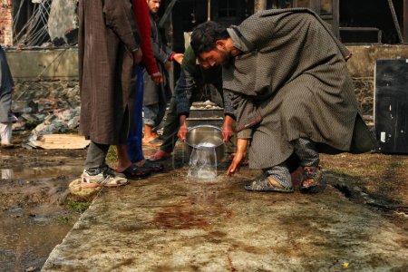 Photo for November 17,2023, Srinagar Kashmir, India : Kashmiri villagers washes the blood stains outside a damaged house during a gunfight in south Kashmirs Kulgam district some 80 kilometers from Srinagar where Five militants were killed - Royalty Free Image